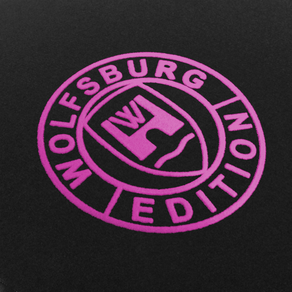 Das Wolfsburg Editions Logo auf einem schwarzen Teppich und das Logo ist in pink.
